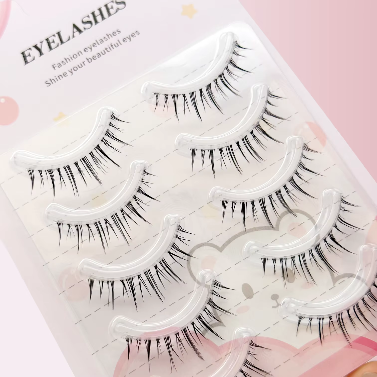 Un coffret de cinq paires de faux cils de style manga avec une base transparente